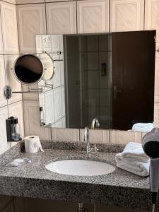 a bathroom counter with a sink and a mirror at Hotel Ze Maria Cambui in Cambuí +136 photos