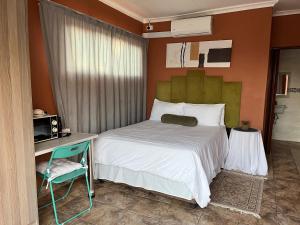 een slaapkamer met een bed, een bureau en een stoel bij 7th Dimension Guesthouse in Zeerust