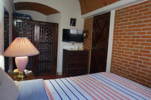 a bedroom with a bed and a tv and a brick wall at Suites Poza Real in Tequisquiapan