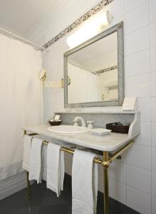 a white sink sitting under a mirror in a bathroom at Solar De La Plaza in Salta