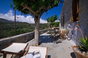 a patio with tables and chairs and a tree at Kallimento-Dimitra in Kissamos