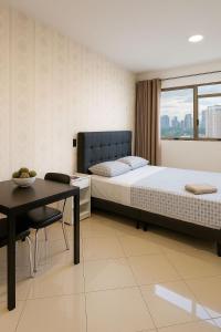 Un dormitorio con una cama y una mesa y una ventana. en Flat Congonhas sp, en São Paulo