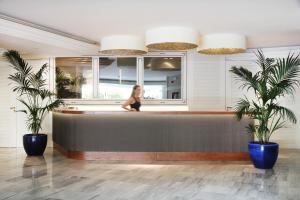 a woman is sitting on a bar in a lobby at Augusta Club & Spa - Adults Only in Lloret de Mar