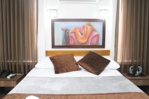 a bedroom with a bed with a painting on the wall at HOTEL NOGAL PLAZA in La Virginia
