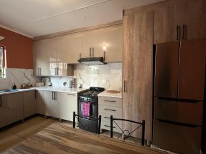 een keuken met witte kasten en een zwarte kachel bij 7th Dimension Guesthouse in Zeerust