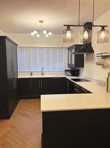 a kitchen with black cabinets and a white counter top at NEW Luxury Neath Center Stay in Neath