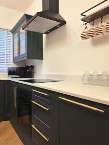 a kitchen with black cabinets and white counter tops at NEW Luxury Neath Center Stay in Neath