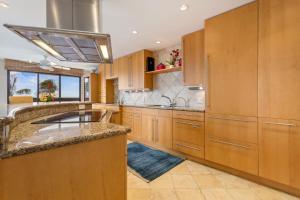 eine große Küche mit Holzschränken und einem Waschbecken in der Unterkunft Kaanapali Alii 2 Bedroom Oceanfront in Hyatt Regency Maui Hotel Heliport