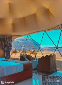 a tent with beds and people riding horses in the desert at Rum thabit camp in Wadi Rum