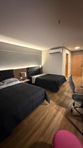 a hotel room with two beds and a chair at Hotel setor marista in Goiânia