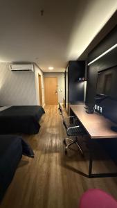 a room with a bed and a desk with a television at Hotel setor marista in Goiânia