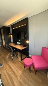 a living room with a pink couch and a desk at Hotel setor marista in Goiânia