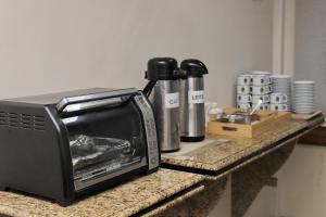 a toaster oven sitting on a counter next to cups at Hotel Macabu in Barra Mansa