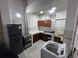 a small kitchen with a black refrigerator and a sink at Apartamento céntrico amplio y seguro in Cali