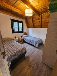 Dos camas en una habitación con techos de madera. en Complejo Bahia de los Sueños, Cabaña Maitenes, en Aluminé