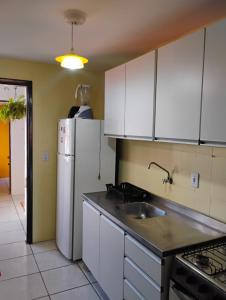 eine Küche mit weißen Schränken und einem weißen Kühlschrank in der Unterkunft Xangrilá, um paraíso perto da praia in Xangri-lá