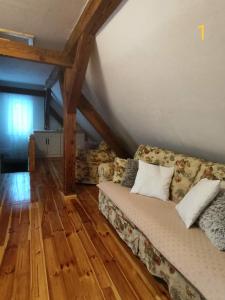 Una sala de estar con un sofá sobre un suelo de madera. en Dom Zawiadowcy, en Budry