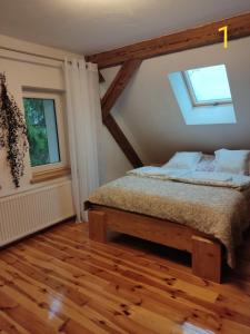 1 dormitorio con cama, ventana y suelo de madera en Dom Zawiadowcy, en Budry
