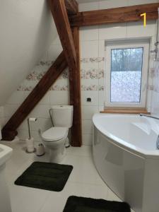 Un baño con bañera, inodoro y ventana. en Dom Zawiadowcy, en Budry