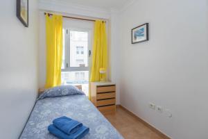 a bedroom with a bed and a window with yellow curtains at Playa Sardina Home with Pool in Sardina +35 photos