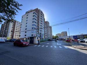 a city street with a building and cars on the road at Newton Flat Apartment in Văleni