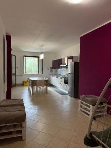 a kitchen with a table and a purple wall at Fun House in Trabia