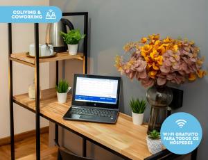 un ordenador portátil en un escritorio con un jarrón de flores en El Misti Suites Buenos Aires, en Buenos Aires