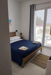 Un dormitorio con una cama con sábanas azules y una ventana. en L'Arco sul Mare, en Porto Cesareo