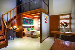 a bedroom with a bed and a desk and a staircase at The Banyumas Villa in Denpasar