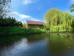 a house next to a river with a building at Charming Country Retreat -Lake View Cottage with Hot tub in Wisbech Saint Mary