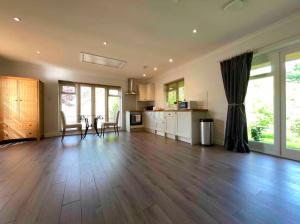a large living room with a wooden floor and a kitchen at Charming Country Retreat -Lake View Cottage with Hot tub in Wisbech Saint Mary