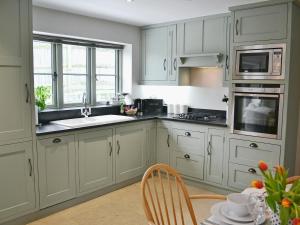 eine Küche mit weißen Schränken und einem Waschbecken und einem Tisch in der Unterkunft Cox Cottage - Pqqq in Pembury