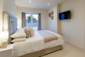 a bedroom with a large bed with a television on the wall at Mudeford Beach Guest Room in Mudeford