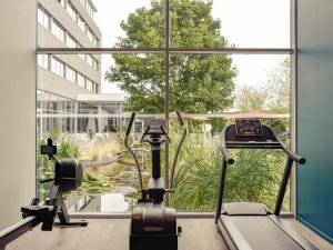 a gym with a treadmill and a large window at Mercure Lyon Genas Eurexpo in Genas
