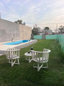 two white chairs and a table next to a pool at Quinta Los Barrera in Cañuelas