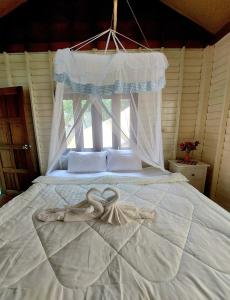 a bedroom with a white bed with a net at Wooden House On The Bay in Ban Bang Chak