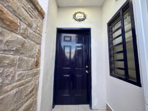 a black door on a house with a stone wall at Mini Suits Limpias y Confortables in Villa de Ojinaga +3 photos