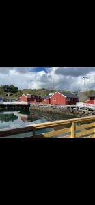 a group of red buildings with a bridge and water at Stinebua in Vestvågøya