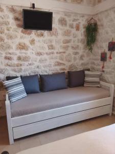 a couch with pillows and a tv on a wall at Afroessa Apartment Ithaca ΙΙ in Vathi, Ithaka
