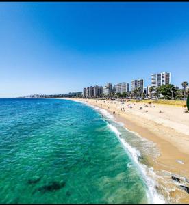 a beach with people and buildings and the ocean at Hermoso departamento en Viña del Mar in Viña del Mar