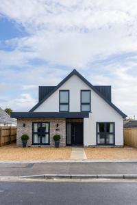 a white house with a black roof at Mudeford Beach Guest Room in Mudeford