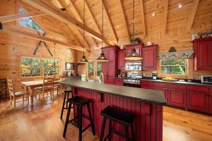 a large kitchen with red cabinets and a dining room at Sugars Cozy Cabin in Sugar Mountain