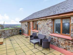 Casa de piedra con patio con sillas y mesa. en The Cartlinhay - Uk35756, en Bideford