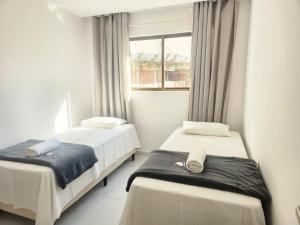 two beds in a room with a window at Sua estadia a 350m da Praia em prédio c/ piscina na melhor localização de Cabedelo-PB | PTAs in Ilha da Restinga +32 photos