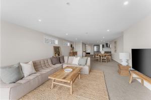 a living room with a couch and a table and a tv at Spacious apartment in Mount Maunganui in Mount Maunganui