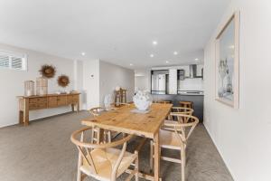 a dining room and kitchen with a wooden table and chairs at Spacious apartment in Mount Maunganui in Mount Maunganui +12 photos
