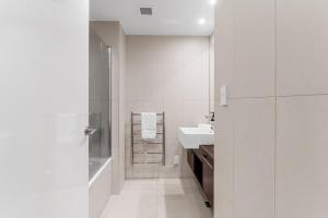 a white bathroom with a sink and a shower at Spacious apartment in Mount Maunganui in Mount Maunganui +12 photos