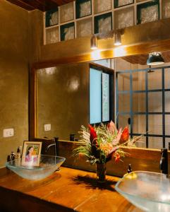 un baño con 2 lavabos y un jarrón de flores sobre una mesa en Salty Enthusiasts Share House & Villas, en Santa Teresa Beach 73 fotos más