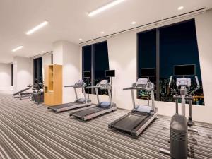 a gym with several tread machines and windows at ibis Styles Ambassador Seoul Yongsan in Seoul