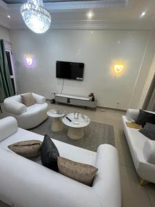 a living room with white furniture and a flat screen tv at Essentiel immo in Brazzaville